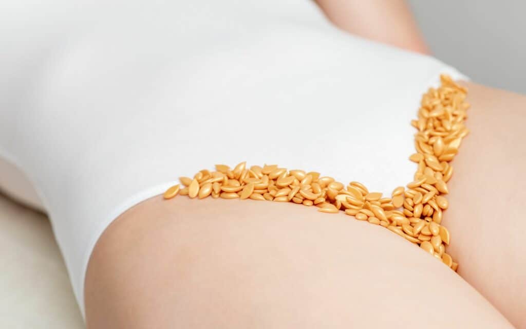 Person wearing white underwear with scattered brown seeds arranged in a V-shape near the waistband.